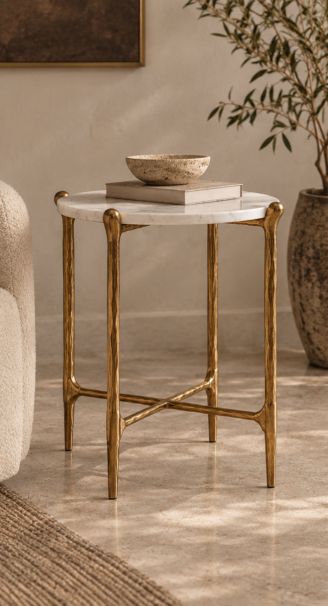 Ausi round side table with a white marble top and a gold metal frame, styled in a warm, neutral-toned room with a bowl and books on top.