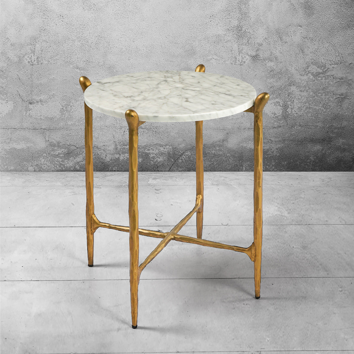 Ausi round marble table with gold legs on a gray concrete floor and background