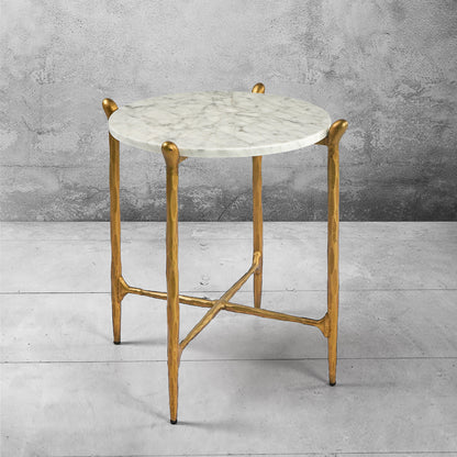 Ausi round marble table with gold legs on a gray concrete floor and background