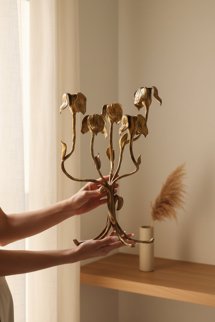 Gold floral candle holder held by a person against a neutral background