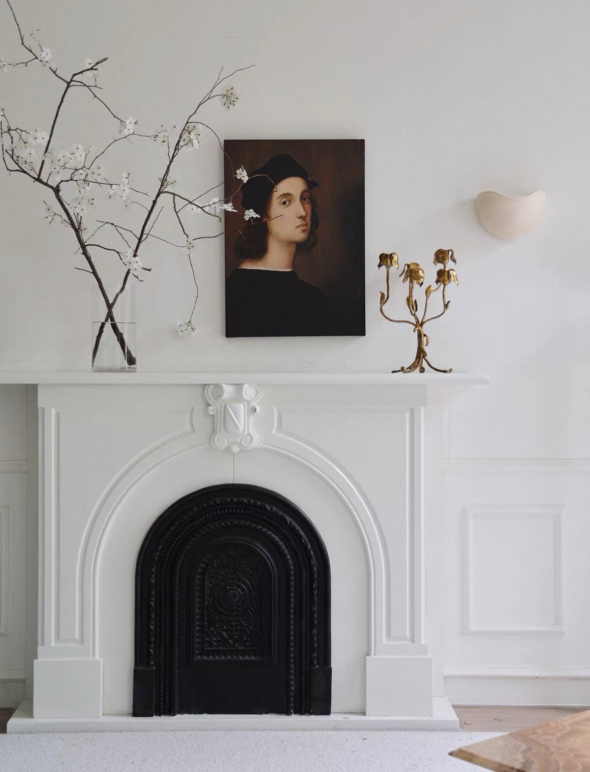 White fireplace with decorative elements and a portrait above it