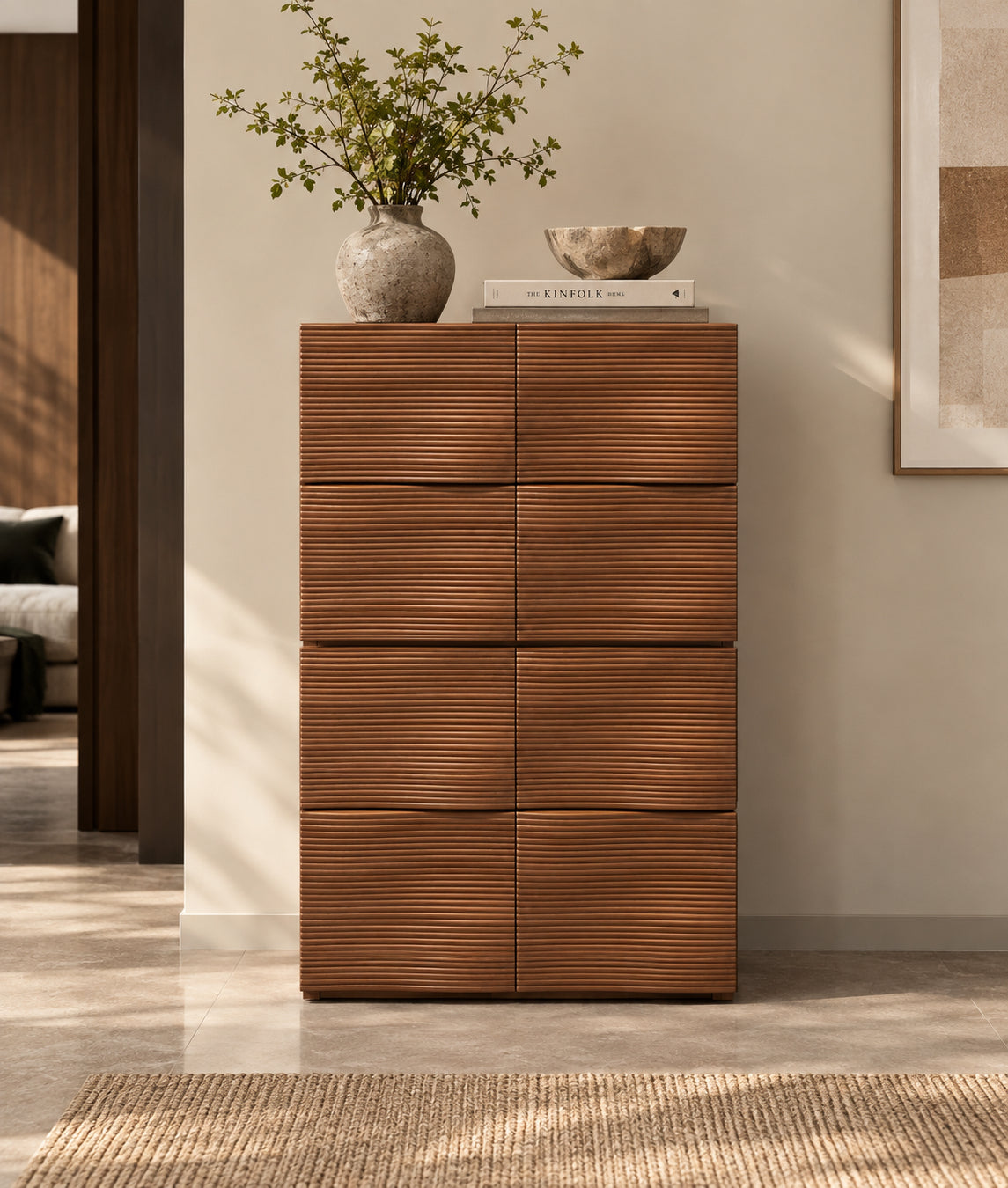 Ausi tall, narrow chest of drawers with six front panels featuring a wavy, ribbed texture in a warm medium brown finish, styled in a modern living room setting with a vase and bowl on top.