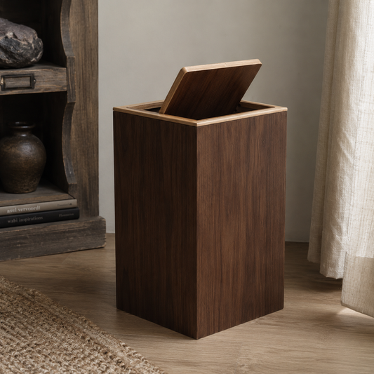 Dark walnut wood trash bin with contrasting light wood lid trim in a warm minimalist interior.