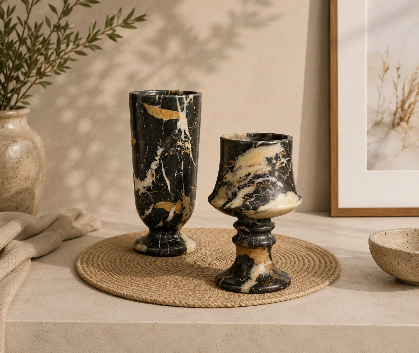 Two marbled black and gold vases on a woven mat with a neutral background