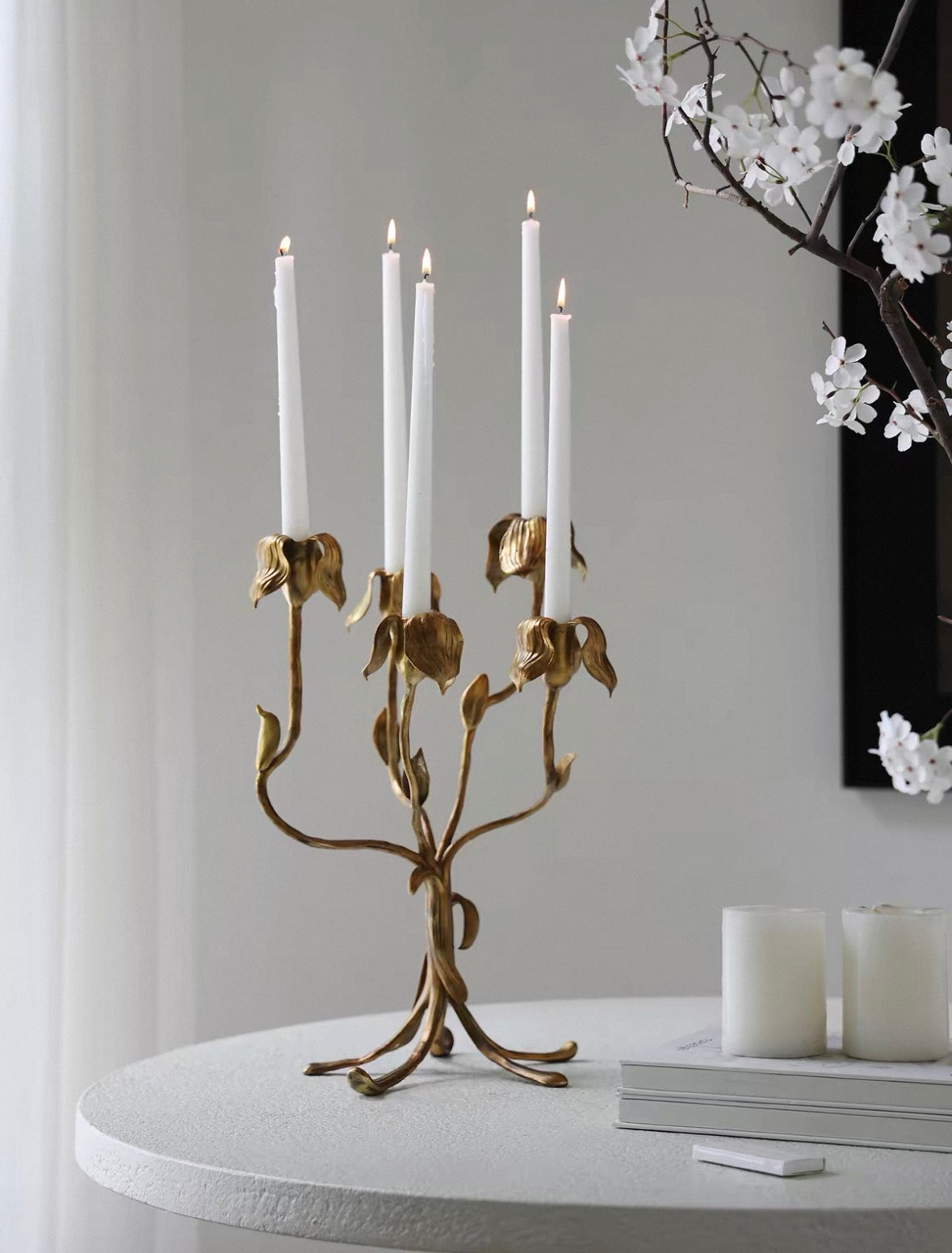 Gold candelabra with white candles on a table against a gray wall