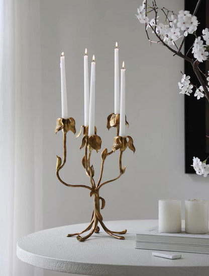 Gold candelabra with white candles on a table against a gray wall