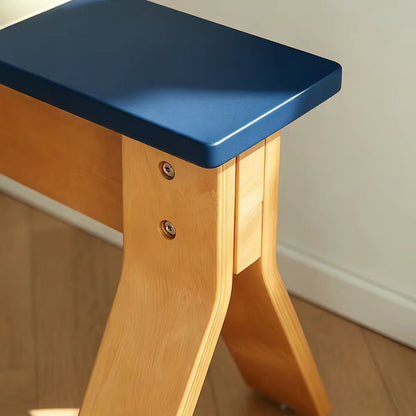 Close-up of a wooden exercise or yoga stool with a matte blue seat and natural light wood legs, set against a neutral indoor background.