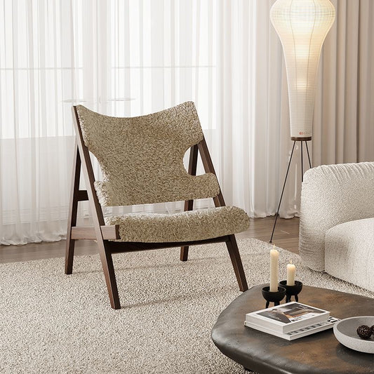 A modern lounge chair with a textured beige bouclé seat and backrest and dark wood legs, styled in a cozy living room next to a white sofa and a floor lamp.