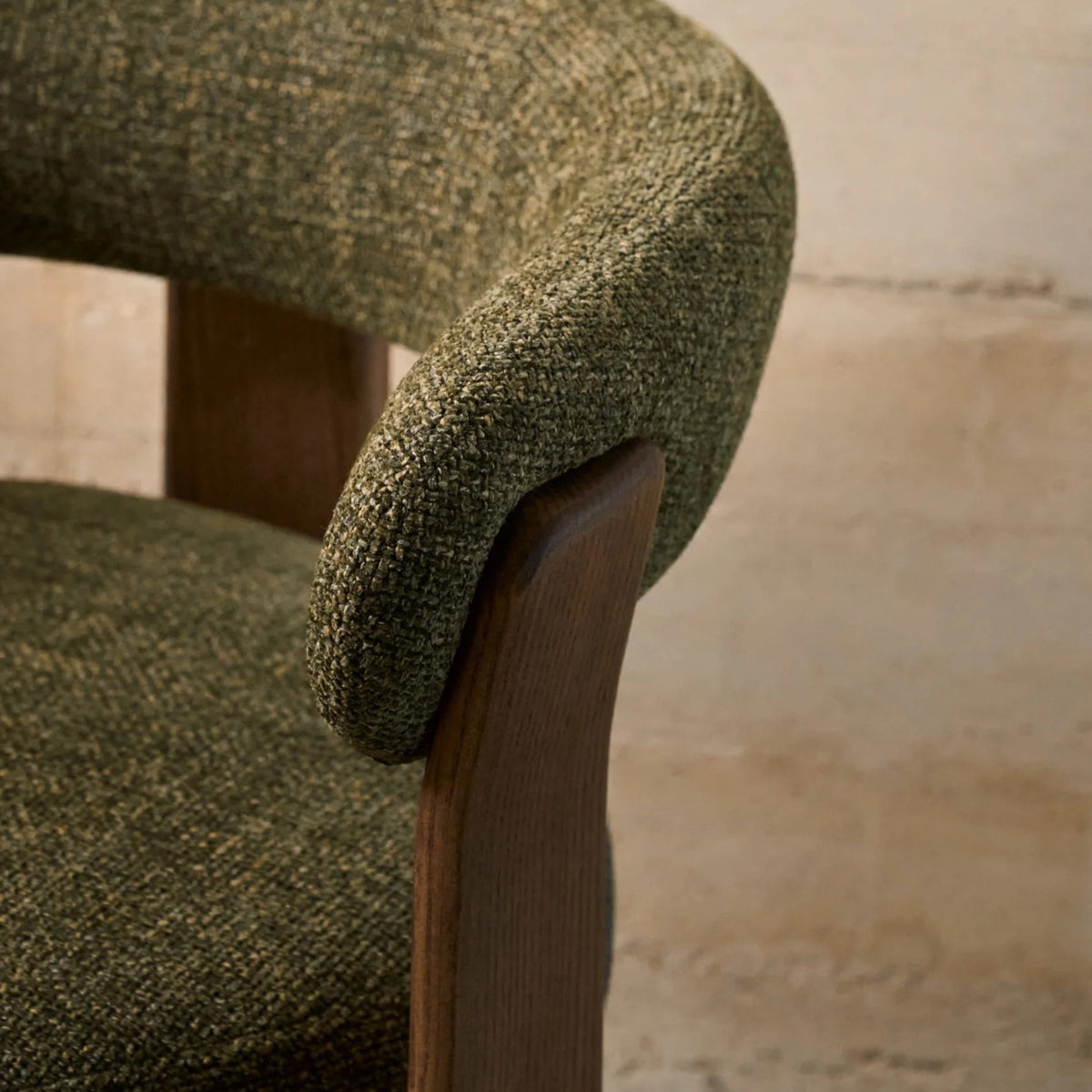 Close-up of olive green textured upholstery and curved wooden chair back support