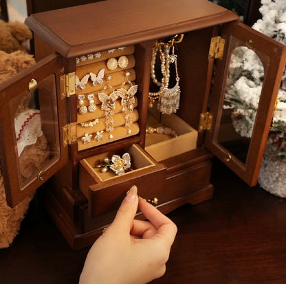 Wooden jewelry box with jewelry inside, held open by a hand.