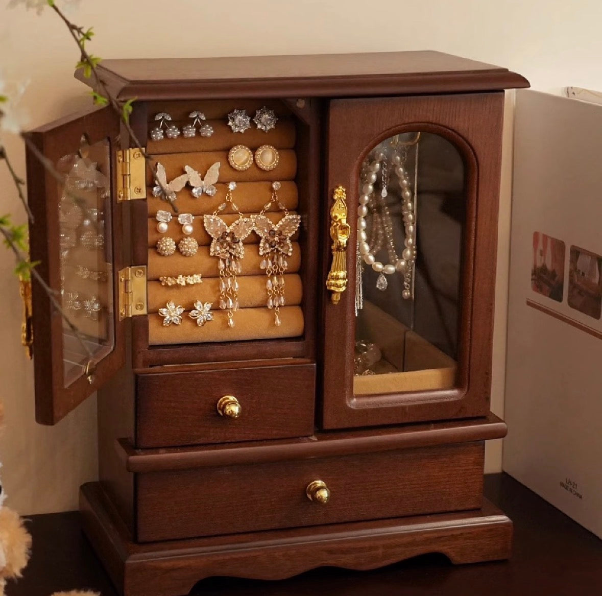 Wooden jewelry cabinet with open doors displaying various earrings.